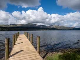 A wooden pier extending over water with mountains in the background at Deer Close in Coniston