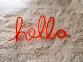A textured wall with the word hello shaped from orange rope at The Stables at Daubeneys in Colerne