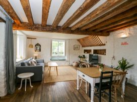 A living room with wooden beams a sofa a coffee table a dining table with chairs and plants at The Stables at Daubeneys in Colerne
