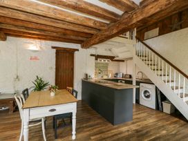 A kitchen and dining area with wooden beams a dining table chairs kitchen appliances and stairs at The Stables at Daubeneys Colerne