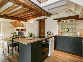 A kitchen with wooden beams wooden floor grey cabinets dining table and chairs at The Stables at Daubeneys Colerne
