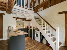A kitchen with wooden flooring a washing machine dishwasher and white staircase at The Stables at Daubeneys Colerne