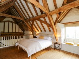 A bedroom with a wooden bed white bedding two bedside tables with lamps wooden beams and a window seat at The Stables at Daubeneys Colerne