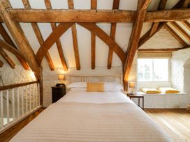 A bedroom with a bed bedside tables lamps and a window seat at The Stables at Daubeneys Colerne