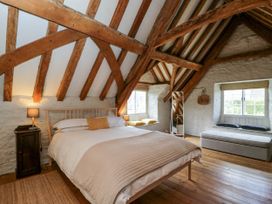A bedroom with exposed wooden beams a double bed two windows and a bench at The Stables at Daubeneys Colerne