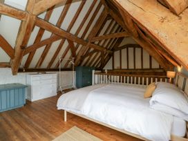 A bedroom with exposed wooden beams a bed a white dresser and a blue cabinet at The Stables at Daubeneys in Colerne