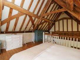 A bedroom loft with exposed wooden beams white chest of drawers blue cabinet and bed at The Stables at Daubeneys Colerne