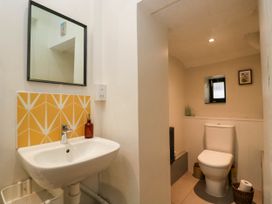 A bathroom with a sink and mirror and a separate toilet area with a small window at The Stables at Daubeneys Colerne
