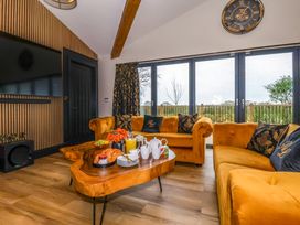 A living room with mustard yellow sofas a wooden coffee table with breakfast items a large wall clock and a flat screen tv at Routhorpe Lodge Bainton near Great Driffield