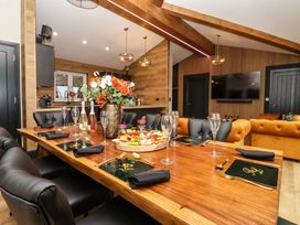 A dining table set with plates glasses cutlery and a floral centerpiece in a room with wood beams and a tv at Routhorpe Lodge in Bainton near Great Driffield