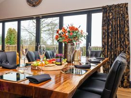 A dining table set with plates glasses cutlery and a flower vase in a room with large windows and patterned curtains at Routhorpe Lodge Bainton near Great Driffield