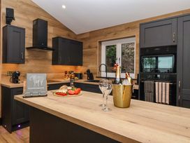 A kitchen with wooden countertops dark cabinets a window with a view and items on the counter including bread tomatoes and a champagne bucket at Routhorpe Lodge in Bainton near Great Driffield