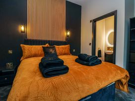 A bedroom with an orange bedspread and folded black towels on the bed at Routhorpe Lodge in Bainton near Great Driffield