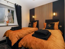 A bedroom with two single beds with orange bedding and black pillows at Routhorpe Lodge in Bainton near Great Driffield