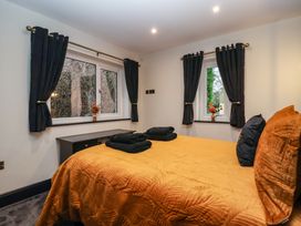 A bedroom with an orange bedspread black curtains on two windows and black folded towels on the bed at Routhorpe Lodge in Bainton near Great Driffield
