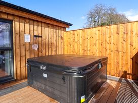 An outdoor hot tub with a cover on a wooden deck surrounded by wooden fencing at Routhorpe Lodge in Bainton near Great Driffield