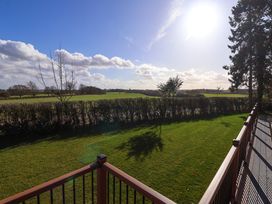 A fenced grassy yard with trees and hedges overlooking open fields at Routhorpe Lodge in Bainton near Great Driffield