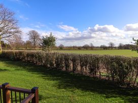 A grassy garden area with a hedge and leafless trees under a partly cloudy sky at Routhorpe Lodge in Bainton near Great Driffield