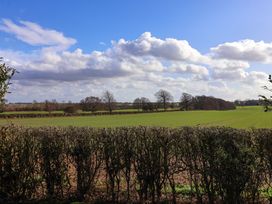 A field with green grass and leafless trees in the background under a partly cloudy sky at Routhorpe Lodge in Bainton near Great Driffield