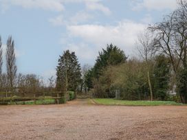 A gravel driveway with a wooden gate and trees on either side at Woodland Retreat Lodge in Brundish near Laxfield