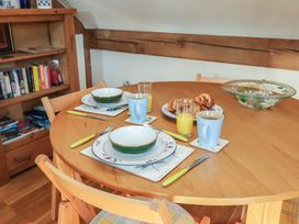 A dining table set with bowls, mugs, glasses of orange juice, croissants, and a glass bowl near a bookshelf at Woodland Retreat Lodge in Brundish near Laxfield