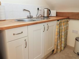 A kitchen counter with a sink kettle microwave and paper towel at Woodland Retreat Lodge Brundish near Laxfield