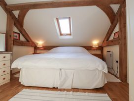 A bedroom with a large bed under a skylight and wooden beams at Woodland Retreat Lodge Brundish near Laxfield