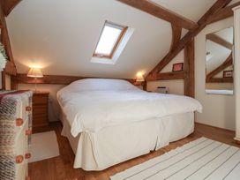A bedroom with a large bed under a skylight and wooden beams at Woodland Retreat Lodge in Brundish near Laxfield
