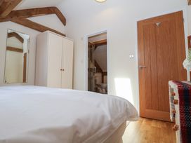 A bedroom with a bed a wardrobe a mirror a wooden door and a door leading to a bathroom at Woodland Retreat Lodge in Brundish near Laxfield