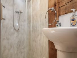 A bathroom with a shower, white sink, wall-mounted ring towel holder and liquid soap at Woodland Retreat Lodge Brundish near Laxfield
