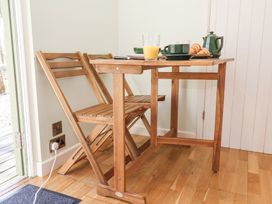 A wooden table with two wooden folding chairs and breakfast items at Woodlands Retreat Shepherd's Hut Brundish near Laxfield