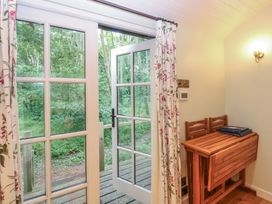 A room with a table and chairs leading to an outdoor area at Woodlands Retreat Shepherd's Hut Brundish near Laxfield