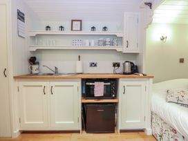 A kitchen area with sink, microwave, kettle, and shelves at Woodlands Retreat Shepherd's Hut Brundish near Laxfield