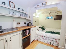 A bedroom with a kitchenette and bed at Woodlands Retreat Shepherd's Hut in Brundish near Laxfield