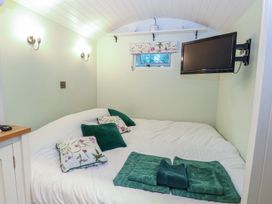 A bedroom with a bed and television at Woodlands Retreat Shepherd's Hut in Brundish near Laxfield