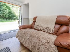 A sofa with a throw blanket in front of a sliding door at Roe Deer Lodge Littlebeck near Sleights
