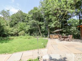 A garden with grass and patio stones at Roe Deer Lodge in Littlebeck near Sleights
