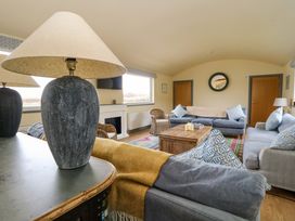 A living room with sofas a wooden coffee table a lamp and wicker chairs at WildLuing Cullipool Isle Of Luing