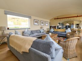 A living room with blue sofas wicker chairs wooden table and dining area at WildLuing in Cullipool Isle Of Luing