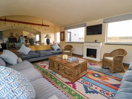 A living room with sofas pillows a wooden coffee table a fireplace and wicker chairs at WildLuing in Cullipool Isle Of Luing