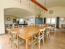 A dining room with a large wooden table surrounded by chairs and a living area visible through an archway at WildLuing Cullipool Isle Of Luing
