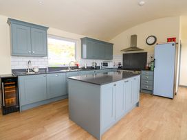 A kitchen with blue cabinets an island a stove a refrigerator and wooden flooring at WildLuing in Cullipool Isle Of Luing