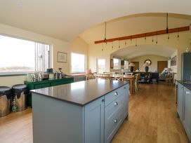 A kitchen island with drawers stools green sideboard and dining table in an open living space at WildLuing in Cullipool Isle Of Luing