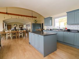 A kitchen and dining area with blue cabinets a kitchen island wooden floor and large dining table at WildLuing Cullipool Isle Of Luing