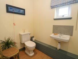 A bathroom with a toilet a sink a small window and a chair with a plant at WildLuing Cullipool Isle Of Luing