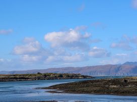 A coastal landscape with rocky shorelines and hills under a blue sky at WildLuing Cullipool Isle Of Luing