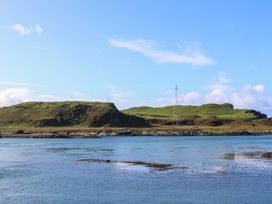 A body of water with an island covered in grass and a metal tower at WildLuing Cullipool Isle Of Luing