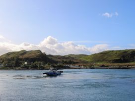 A boat on water with hills and houses in the background at WildLuing Cullipool Isle Of Luing