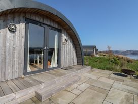 Wooden pod cabins with glass doors on a stone patio overlooking water and hills at WildLuing in Cullipool Isle Of Luing