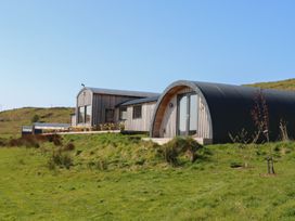 A curved wooden and metal building on a grassy hillside at WildLuing in Cullipool Isle Of Luing